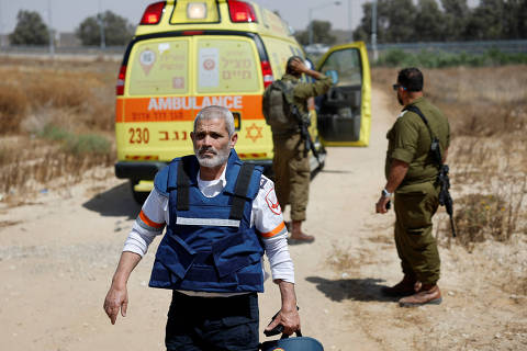 An Israeli medic walks near soldiers and an ambulance after Palestinian Islamist group Hamas claimed responsibility for an attack on Kerem Shalom crossing, near Israel's border with Gaza in southern Israel, May 5, 2024. REUTERS/Amir Cohen ORG XMIT: LIVE