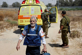 An Israeli medic walks near soldiers and an ambulance after Palestinian Islamist group Hamas claimed responsibility for an attack on Kerem Shalom crossing
