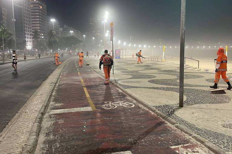 Imagem mostra garis limpando praia de Copacabana durante madrugada