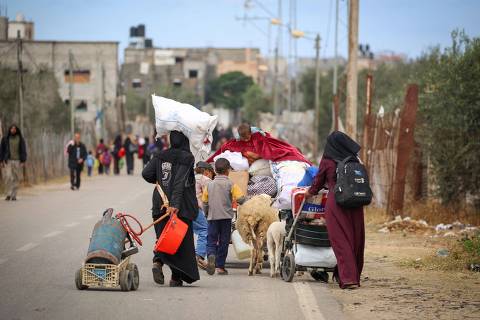 TOPSHOT - Displaced Palestinians in Rafah in the southern Gaza Strip carry their belongings as they leave following an evacuation order by the Israeli army on May 6, 2024, amid the ongoing conflict between Israel and the Palestinian Hamas movement. (Photo by AFP)