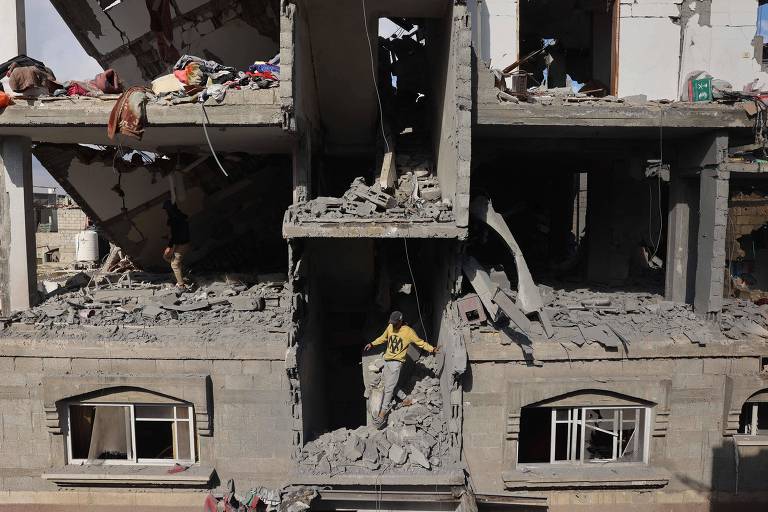 Palestino em meio a prédio destruído em Rafah, no sul da Faixa de Gaza
