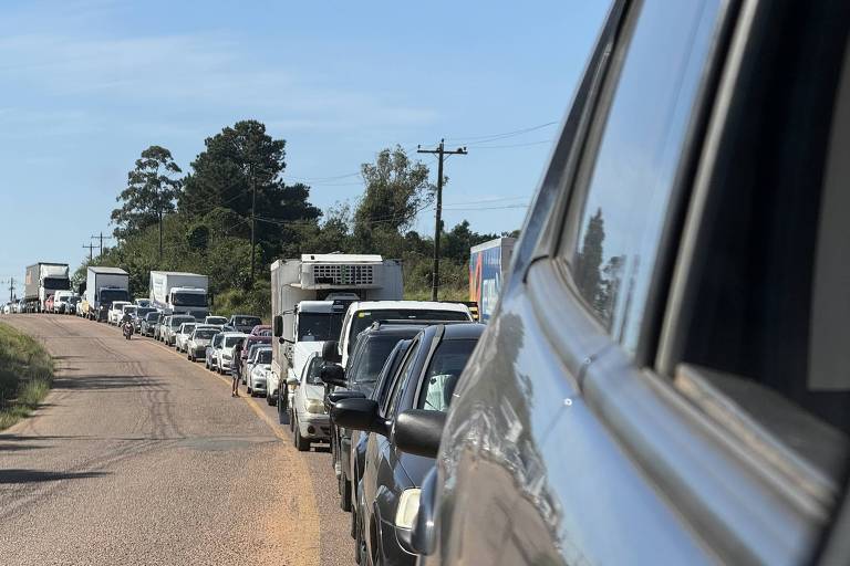 Na foto, uma fila de carros e caminhões se alinha em apenas um lado da estrada. A outra mão segue livre.