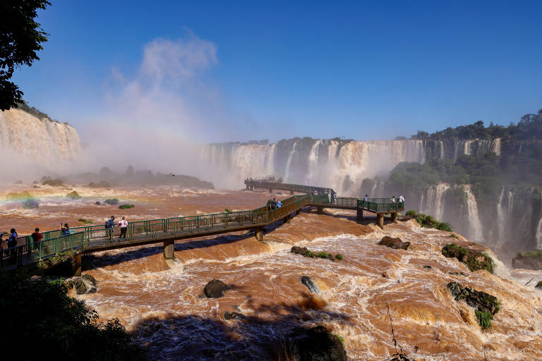 Pessoas visitam as Cataratas do Iguaçu, que atualmente estão com capacidade total de água devido às chuvas no sul do Brasil