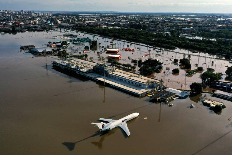 Aeroporto visto de cima com muita água na pista; há um avião no meio da água, com a parte de baixo submersa