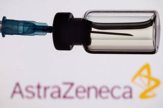 FILE PHOTO: A vial and a syringe are seen in front of a displayed AstraZeneca logo, in this illustration taken