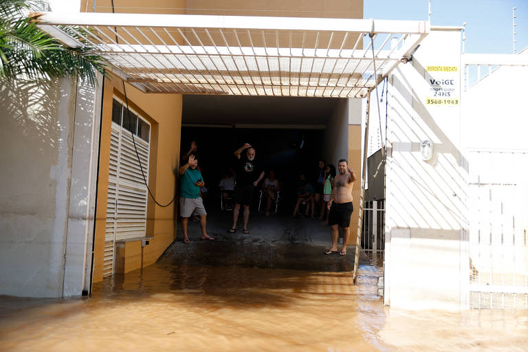 O empresário Vardilei Moura e seus vizinhos na garagem do prédio no centro de São Leopoldo (RS), que está alagado
