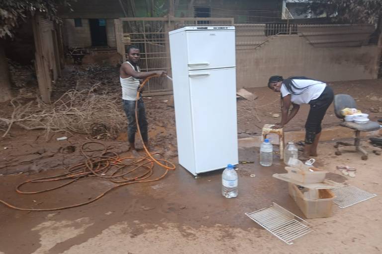 Os angolanos Joel Diasivi, 32, e sua mulher Ntoto Kumbu Rodiane, 24, lavam a geladeira para tentar salvá-la no município de Lajeado (RS), onde as águas do rio Taquari atingiram o segundo andar das casas
