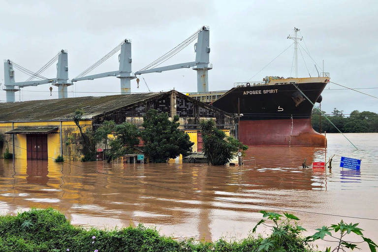 Navio passa no Cais Mauá parcialmente inundado no centro de Porto Alegre; o nível do lago Guaíba baixa lentamente, mas ainda está muito acima do nível