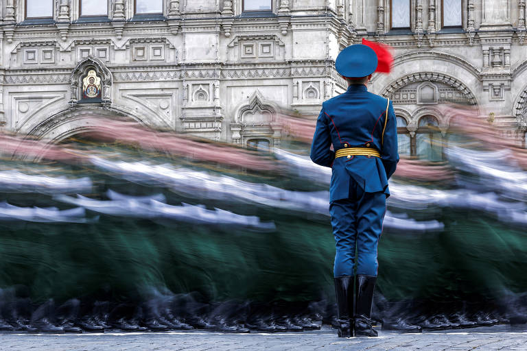 Em imagem com movimento, militares russos marcham em colunas diante de uma guarda de honra durante um desfile militar em frente á um prédio histórico.