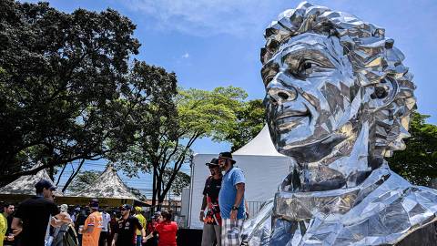 F1 fans pose for a picture in front of an sculpture of late Brazilian F1 driver Ayrton Senn at the Autodromo Jose Carlos Pace racetrack, also known as Interlagos, in Sao Paulo, Brazil, on November 13, 2022, ahead of the Formula One Brazil Grand Prix. - Produced by artist Lalalli Senna, niece of the three-time world champion driver, the work is made of polished aluminum, is 3.5 meters high, weighs 550 kilograms and is part of the celebrations for the 50th anniversary of the Brazilian F1 Grand Prix. (Photo by NELSON ALMEIDA / AFP) ORG XMIT: NAL003