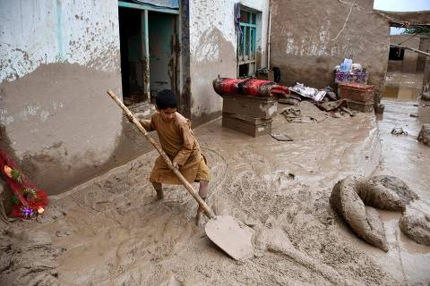 TOPSHOT - An Afghan boy shovels mud from the courtyard of a house following flash floods after heavy rainfall at a village in Baghlan-e-Markazi district of Baghlan province on May 11, 2024. More than 300 people were killed in flash flooding in Afghanistan's northern province of Baghlan, the World Food Programme said on May 11. (Photo by Atif Aryan / AFP)