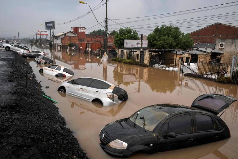 Na foto, carros estão parcialmente submersos em uma via
