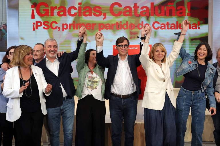 Grupo de seis pessoas brancas comemora, levantando os braços, em frente à frase escrita em vermelho: "Gracias, Cataluña"