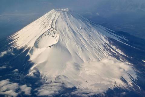 This photo taken on January 30, 2024 shows an aerial view of Mount Fuji, Japan's highest mountain at 3,776 meters (12,389 feet), from the window of a passenger jet. An online booking system for Mount Fuji's most popular trail was announced on May 13, 2024 by Japanese authorities trying to fight overtourism on the active volcano. (Photo by Richard A. Brooks / AFP)