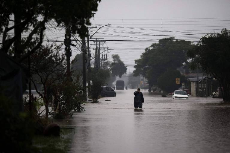 Homem caminha em meio à inundação na cidade de Eldorado do Sul (RS)