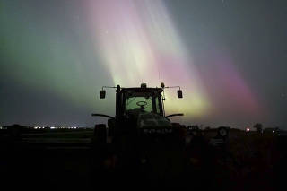 In an undated photo from Tiffany Graham, an aurora over a tractor at O'Connor Family Farms near Blooming Prairie, Minn. (Tiffany Graham via The New York Times)