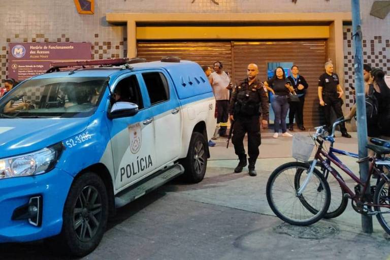A imagem mostra uma viatura da Polícia Militar em frente a um prédio