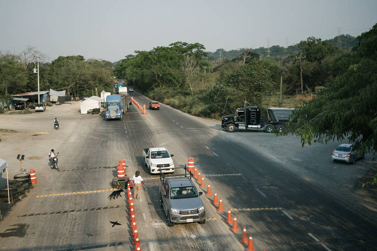 Carros fazem fila em estrada, cercados por cones, para verificação em "checkpoint" no México
