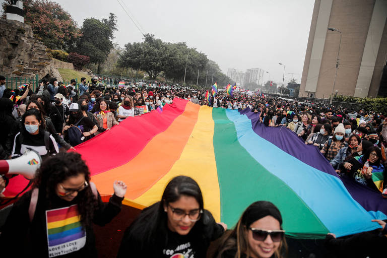 Multidão segura enorme bandeira colorida, símbolo da comunidade LGBTQIA+