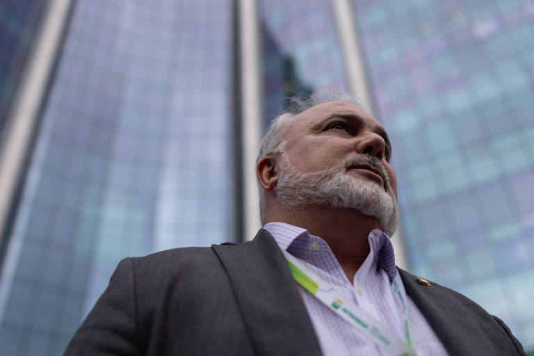 Jean Paul Prates é um homem branco, de cabelo e barba grisalha. Ele olha para o céu após sair do prédio da Petrobras.
