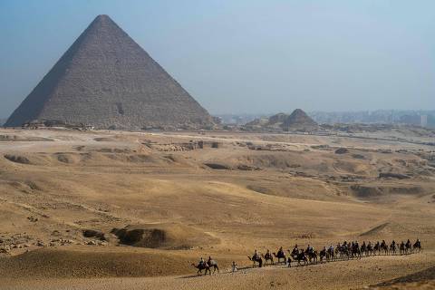 Tourists ride camels near the Great Pyramid of Khufu (Cheops) at the Giza Pyramids Necropolis on the outskirts of Giza on May 3, 2024. (Photo by Jewel SAMAD / AFP)