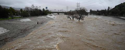 TOPSHOT - A person walks to the edge of the raging Los Angeles River as the second and more powerful of two atmospheric river storms inundate Los Angeles, California, on February 5, 2024. Swaths of the US state of California were flooded on Monday and hundreds of thousands of people were without power after a dangerous storm brought heavy rains and prompted a state of emergency. (Photo by Robyn Beck / AFP)
