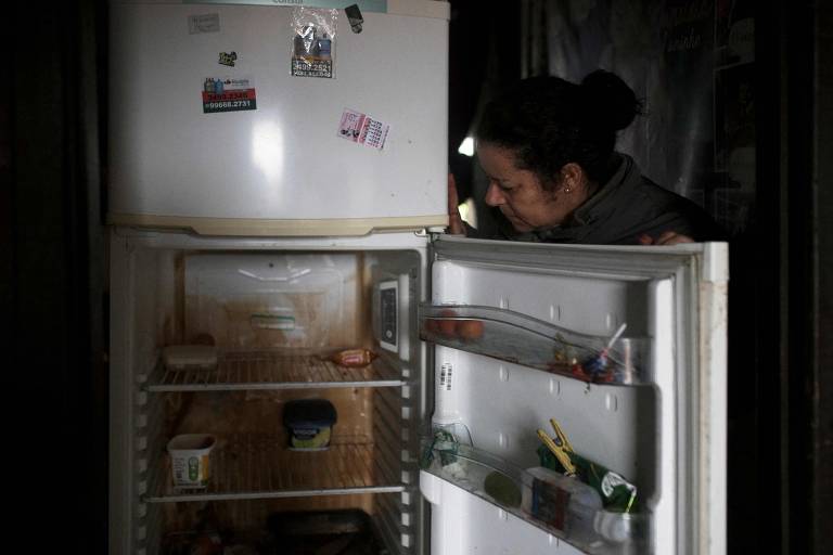 Janete Gomes, moradora de Eldorado do Sul, observa geladeira destruída pela enchente em sua casa