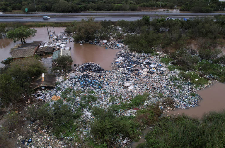 Lixo acumulado próximo a rodovia em área alagada em Porto Alegre
