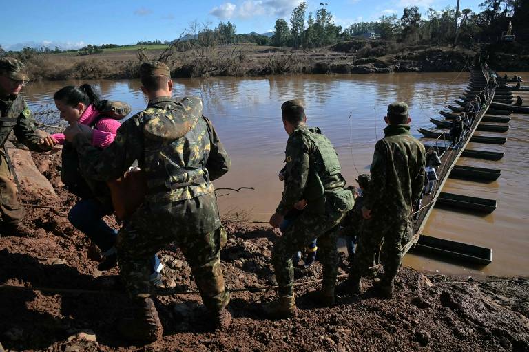 Militares ajudam moradores atravessar passarela improvisada sobre o rio Forquilha