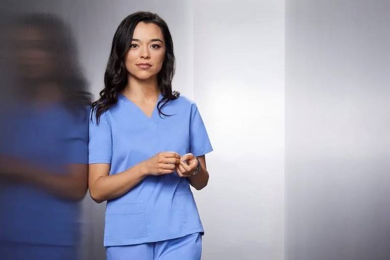 Em foto colorida, mulher de uniforme de enfermeira posa para foto
