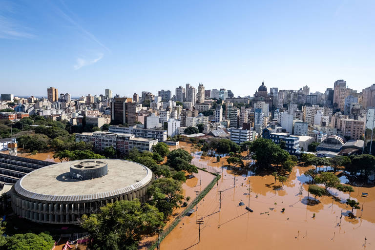 No canto inferior esquerdo, a sede da Procergs, em formato circular, com três andares. No entorno,  centro histórico de Porto Alegre completamente alagado. 