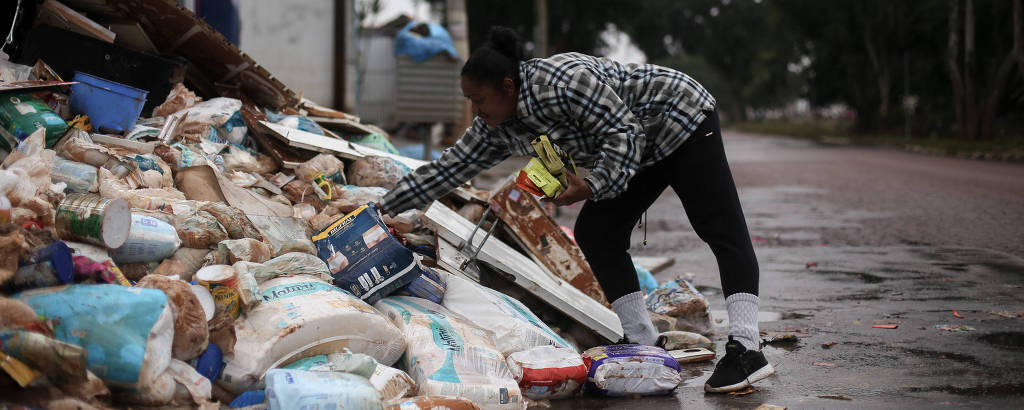 Moradora do bairro Santa Rita, em Guaíba, Tailaine da Silva Moura colhe produtos de farmácia atingida pela enchente