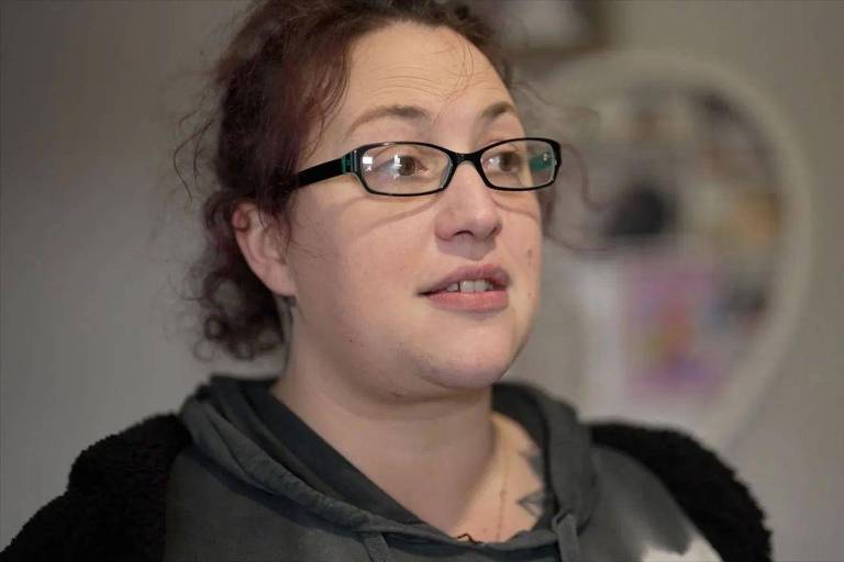 Gemma, uma das vítimas da Depher, mulher branca com cabelos castanhos; ela usa óculos
