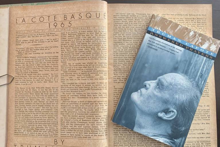 Páginas de uma revista antiga abertas com um livro de capa azul sobre as páginas