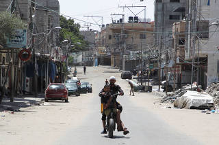 Palestinians ride a motorcycle in a nearly deserted street as people continue to flee Rafah due to an Israeli ground operation, in Rafah, in the southern Gaza Strip