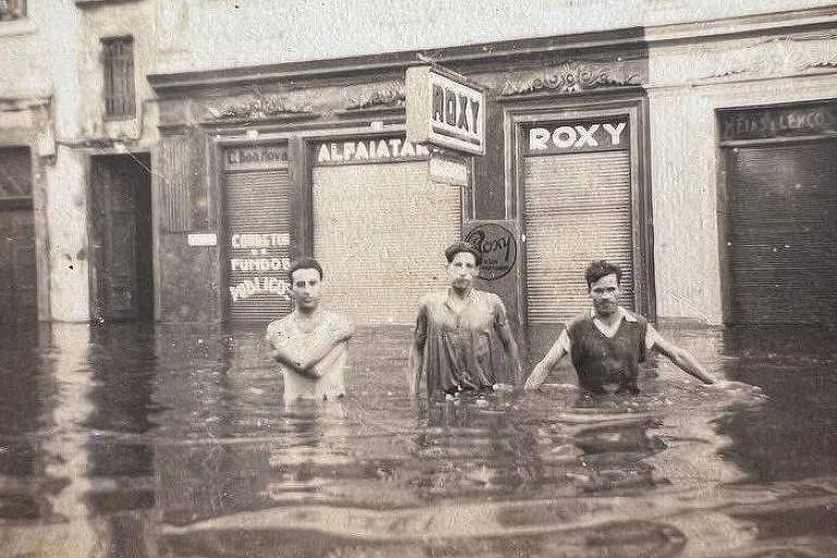 Três homens com a água até a cintura em rua alagada, a enchente de 1941 era até recentemente a pior da história de Porto Alegre