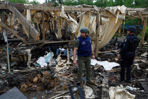 SENSITIVE MATERIAL. THIS IMAGE MAY OFFEND OR DISTURB A war crimes prosecutor and a police officer stand next to the bodies of people killed by a Russian missile strike on a resort compound in Kharkiv, amid Russia's attack on Ukraine May 19, 2024. REUTERS/Valentyn Ogirenko ORG XMIT: SSS-PPP-OGI016
