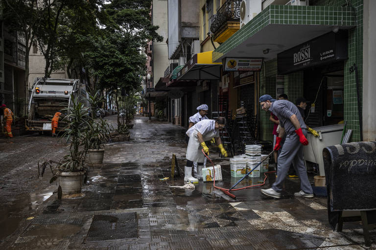 Pessoas em calçada de restaurante com equipamentos de limpeza e caixas empilhadas