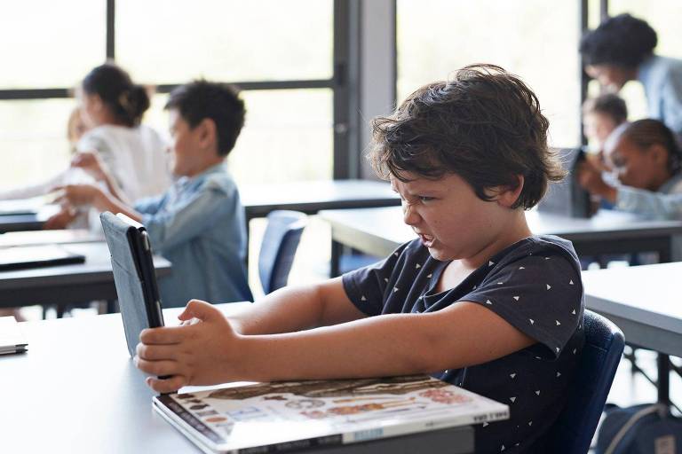 Criança com tablet em sala de aula
