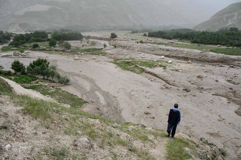 Um homem afegão está no local das enchentes repentinas em Pashah Qol, na província de Baghlan