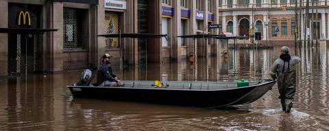 Men navigate a boat through a flooded street in downtown Porto Alegre, Rio Grande do Sul State, Brazil, on May 19, 2024. Porto Alegre, the Brazilian metropolis left submerged after torrential rains, had been lulled into a 