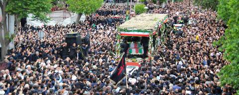 People participate in a funeral procession alongside a lorry carrying the coffins of president Ebrahim Raisi and his seven aides in Tabriz, East Azerbaijan province, on May 21, 2024. Tens of thousands of Iranians gathered on May 21 to mourn Raisi and seven members of his entourage who were killed in a helicopter crash on a fog-shrouded mountainside in the northwest. (Photo by ATA DADASHI / FARS NEWS AGENCY / AFP) ORG XMIT: AK036