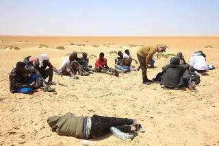 Migrants from Africa rest while they are stranded in the desert on the Libyan-Tunisian border near Al-Assah