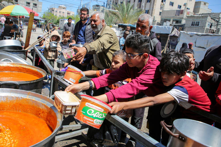 Palestinos se reúnem para receber alimentos preparados por organização em Rafah, no sul de Gaza