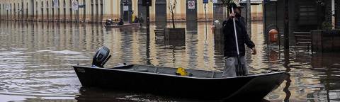TOPSHOT - A man navigates a boat through a flooded street in front of the public market in downtown Porto Alegre, Rio Grande do Sul State, Brazil, on May 19, 2024. Porto Alegre, the Brazilian metropolis left submerged after torrential rains, had been lulled into a 