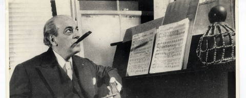 O maestro e compositor Heitor Villa-Lobos é retratado no seu aniversário de 70 anos, em 5 de março de 1957, em frente ao piano tocando os instrumentos típicos de suas obras, reco-reco e afoxé TODOS OS DIREITOS RESERVADOS, PARA AUTORIZAÇÃO CONTATAR HERDEIRA DE VILLA-LOBOS, MARISA GANDELMAN   Credito  Museu Villa Lobos/ Ibram/ MTUR