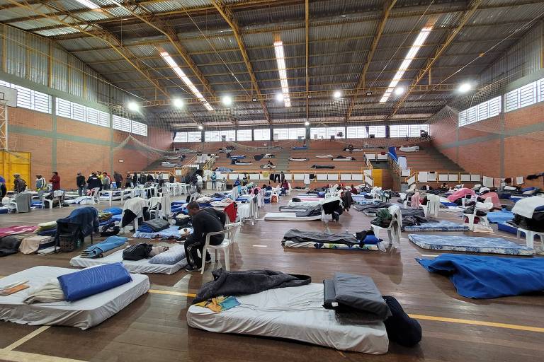 Na foto, um ginásio com colchões espalhados pelo assoalho abriga moradores de rua