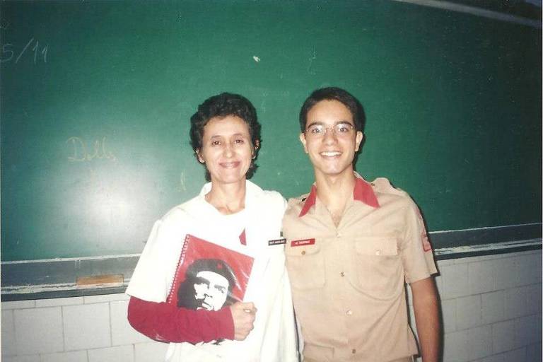 Professora segura caderno com o rosto de Che Guevara com aluno com uniforme do Colégio Militar
