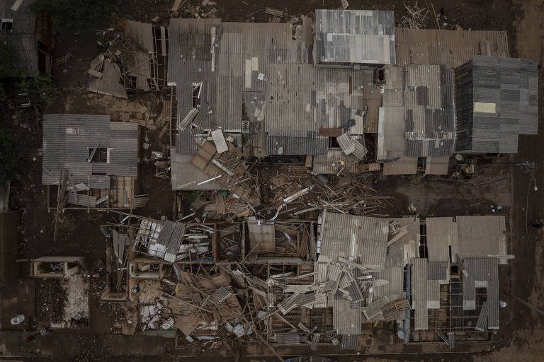 Vista aérea de uma construção devastada, possivelmente após um desastre natural. A imagem mostra escombros dispersos, com partes do edifício desmoronadas e materiais de construção espalhados caoticamente