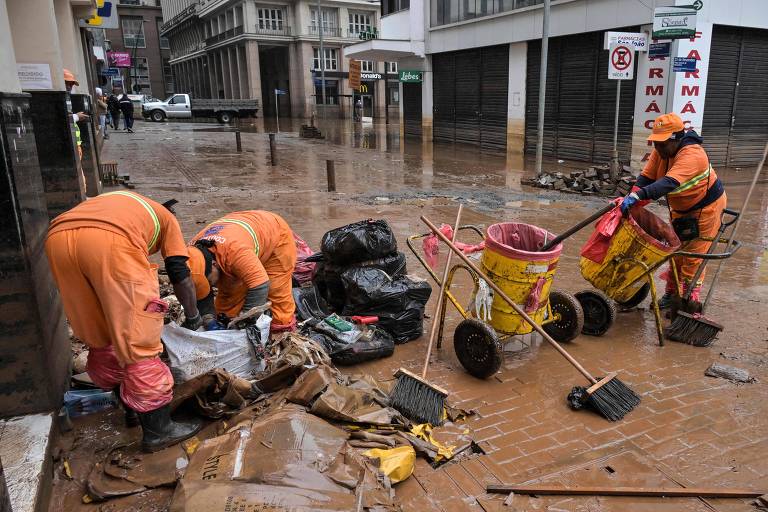 Na foto, trabalhadores de limpeza vestidos de laranja operam no centro de Porto Alegre